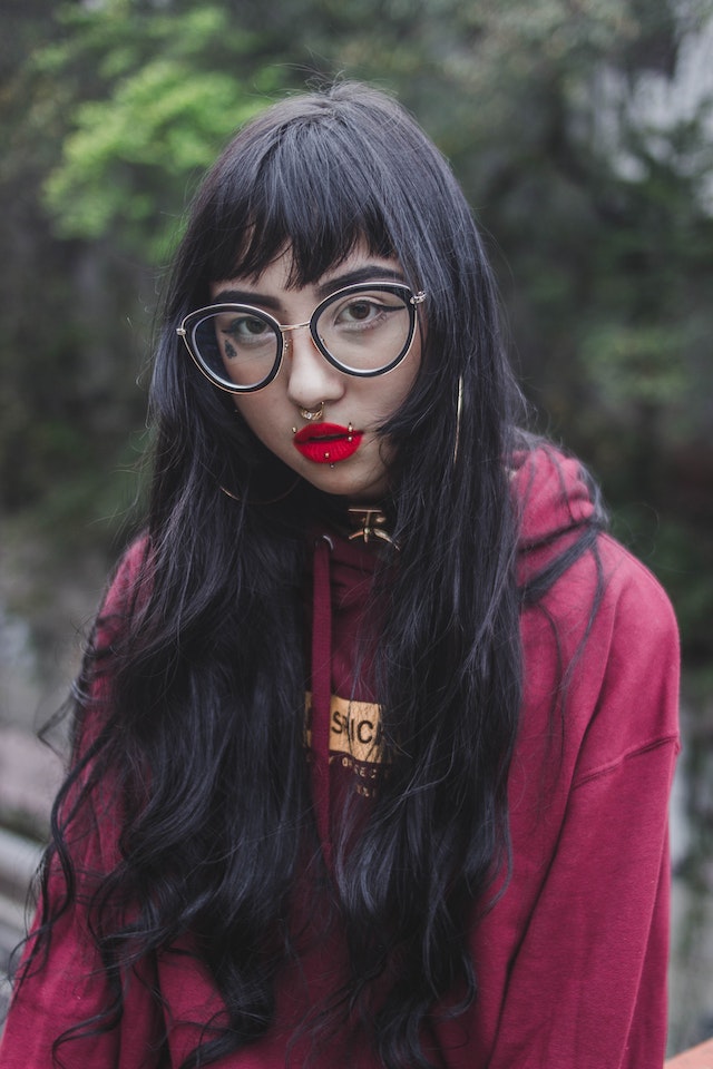 jeune femme avec des lunettes et des piercings sur le visage