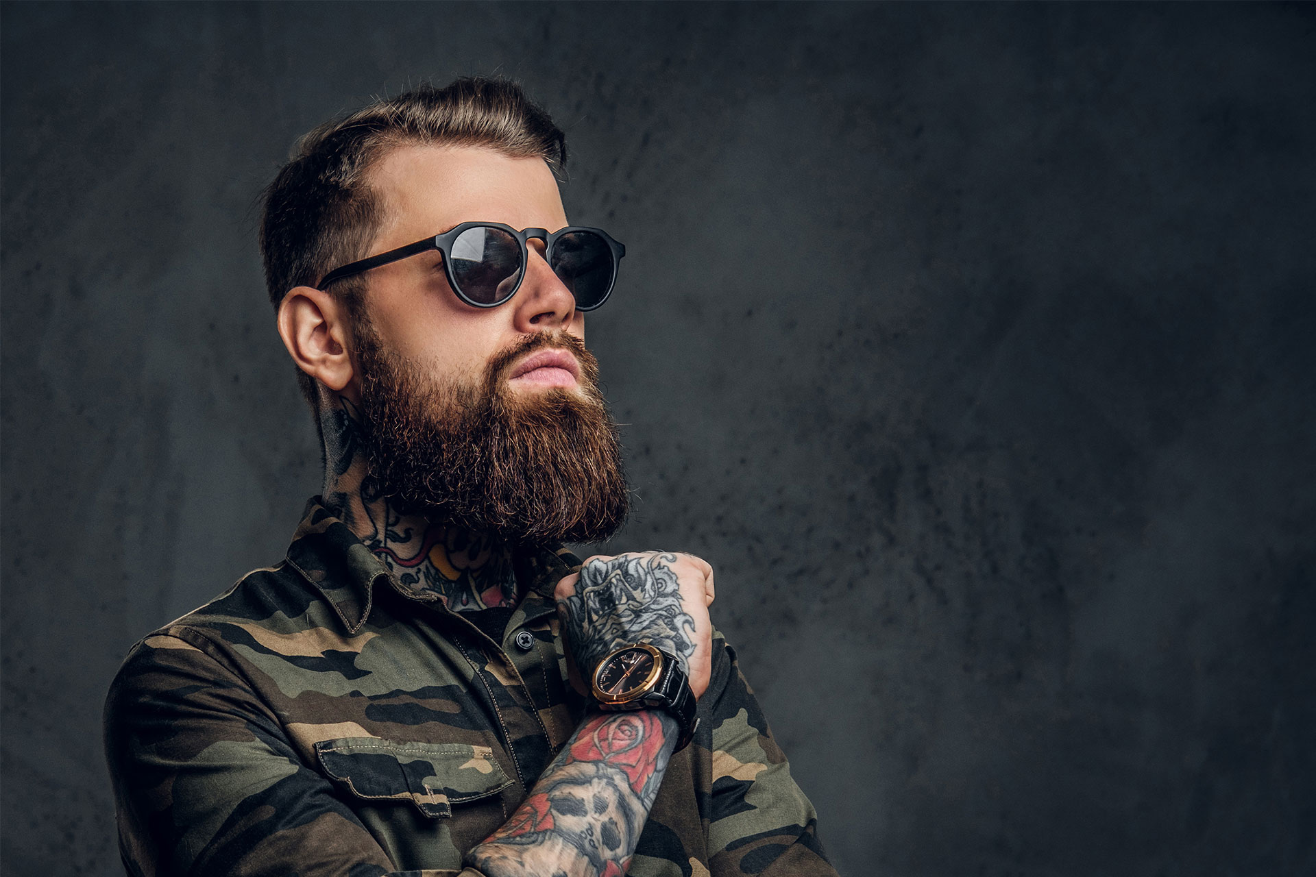 jeune homme tatoué, barbu portant des lunettes de soleil